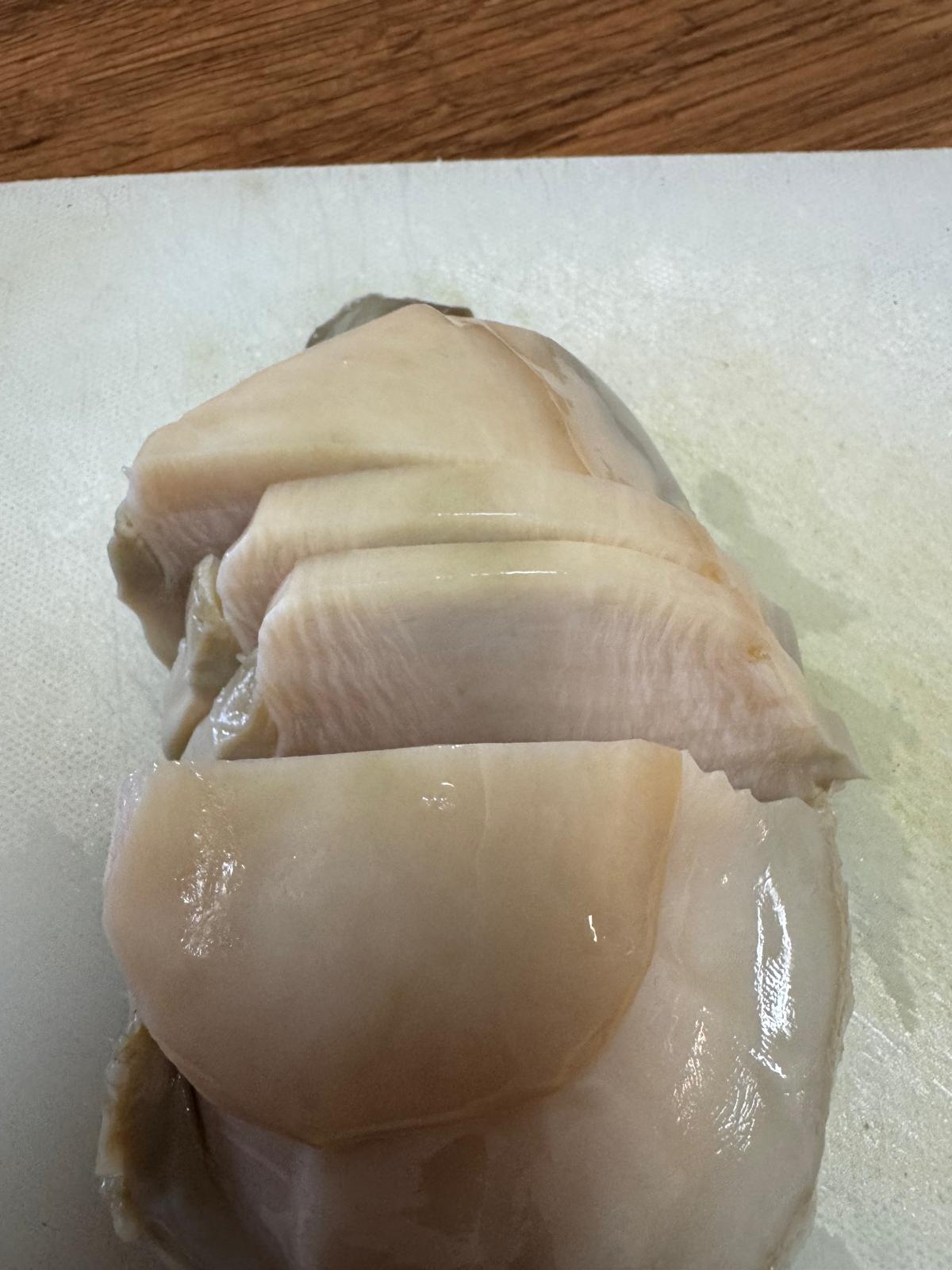 Sliced raw abalone on a cutting board